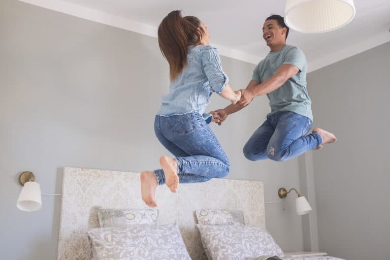 Young couple love life together at home and jump in the air in the bedroom - new house buy